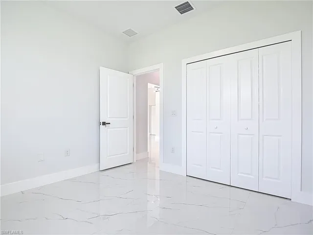 Unfurnished bedroom featuring light marble finish flooring and a closet