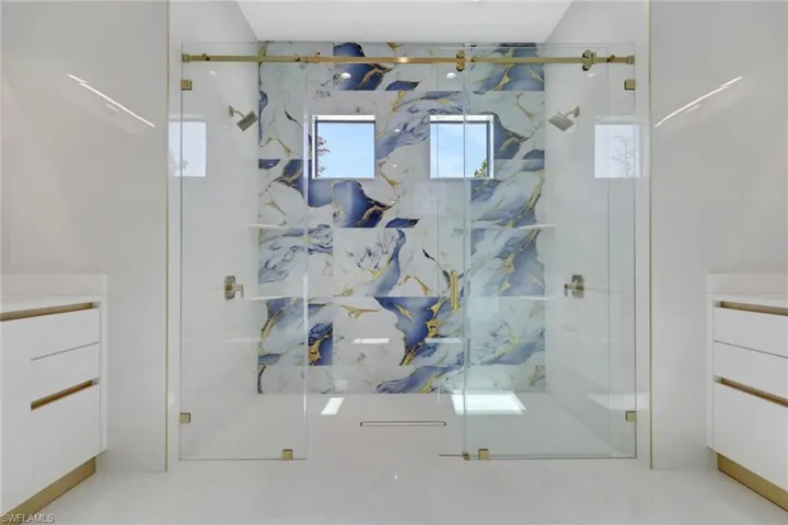 Bathroom with vanity and a marble finish shower