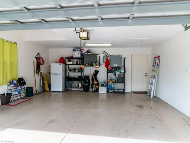 Garage with a garage door opener and white refrigerator