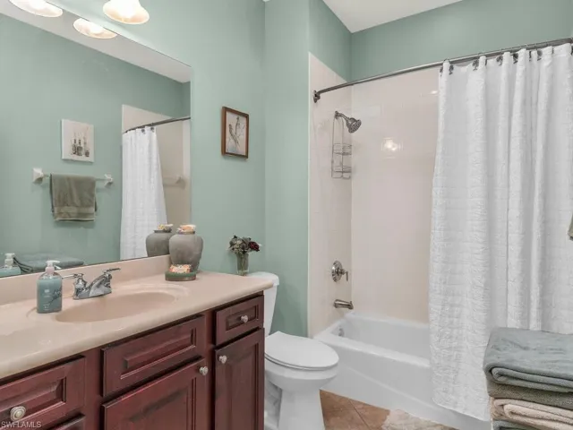 Full bathroom with toilet, vanity, tile patterned floors, and shower / bathtub combination with curtain