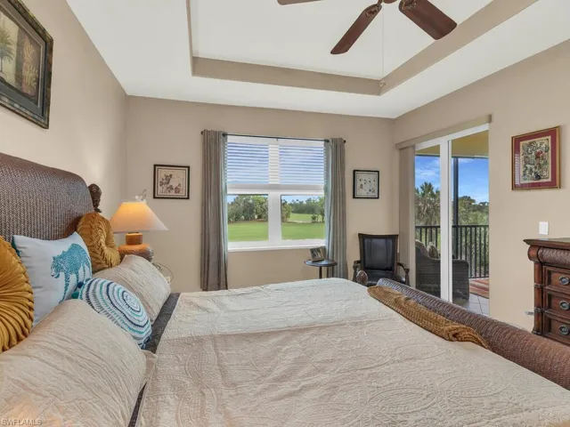 Bedroom featuring access to exterior, multiple windows, ceiling fan, and a tray ceiling