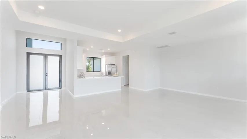 Unfurnished living room featuring sink, french doors, and a tray ceiling