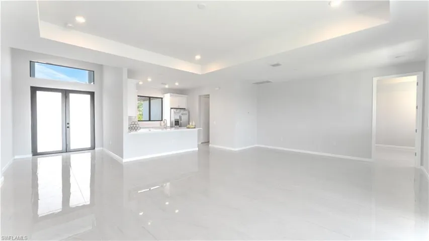 Unfurnished living room with sink, french doors, and a tray ceiling