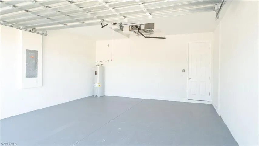 Garage featuring electric panel, a garage door opener, and electric water heater