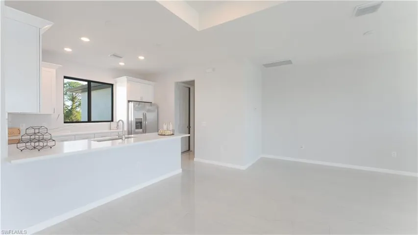 Kitchen featuring white cabinets, stainless steel fridge, light tile patterned floors, and sink
