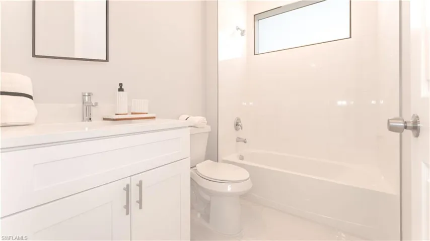 Full bathroom featuring vanity, tiled shower / bath combo, and toilet