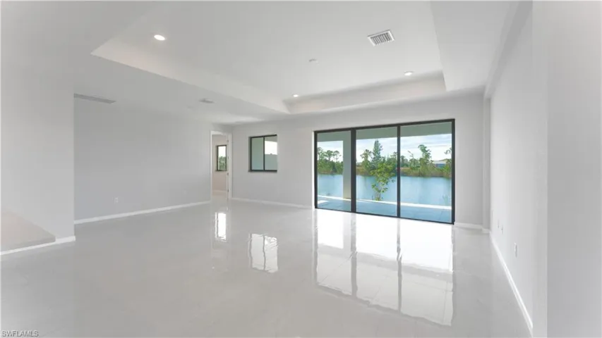 Unfurnished room with light tile patterned floors, a tray ceiling, and a water view