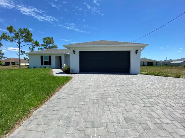 View of front of property featuring a garage and a front lawn