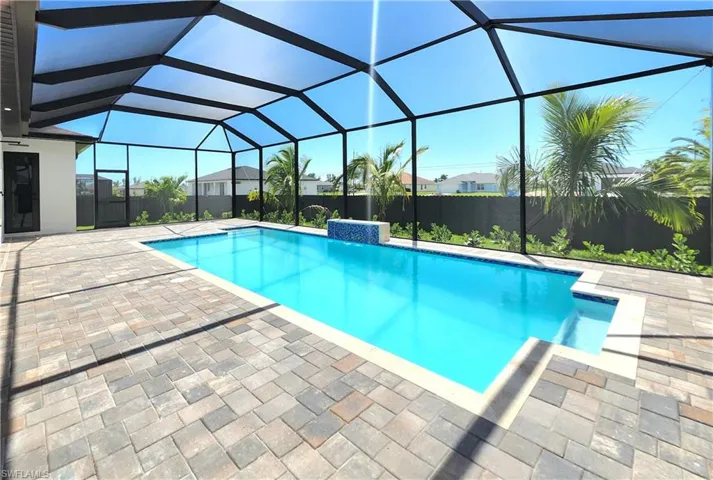 View of pool featuring a sunroom, a patio, and glass enclosure