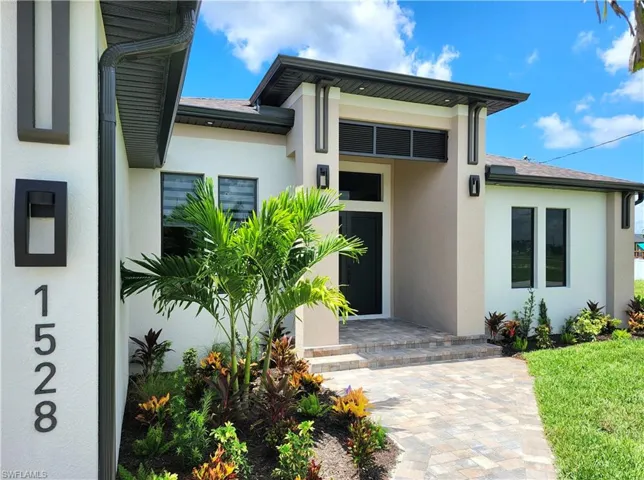 View of exterior entry featuring stucco siding and roof with shingles
