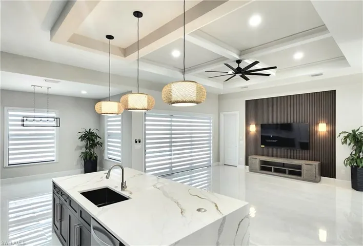 Kitchen featuring light stone countertops, healthy amount of natural light, hanging light fixtures, recessed lighting, and beamed ceiling