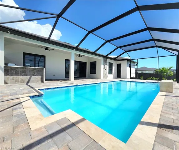 View of swimming pool featuring ceiling fan, a sunroom, a patio area, and glass enclosure