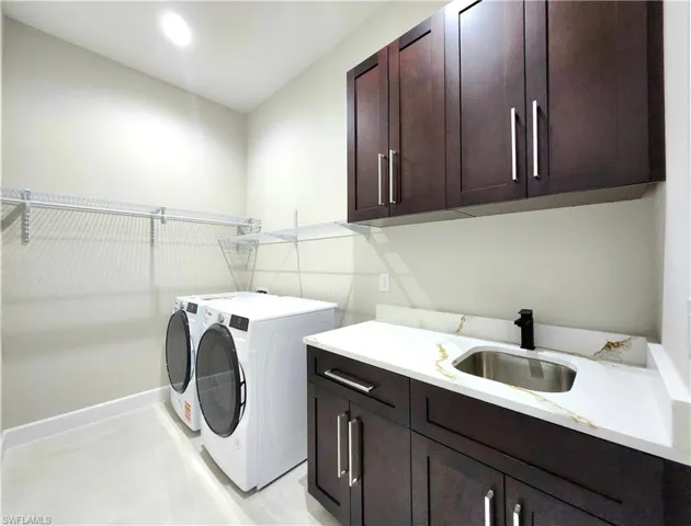 Laundry area featuring cabinet space, washer and clothes dryer, and light tile patterned floors