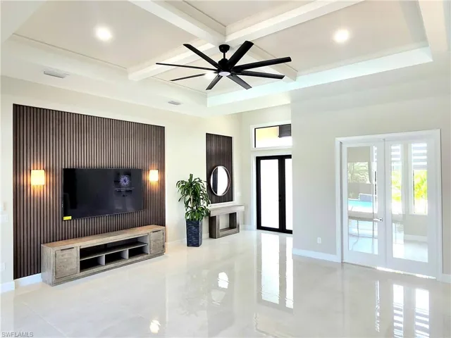 Unfurnished living room featuring french doors, beamed ceiling, coffered ceiling, and a ceiling fan