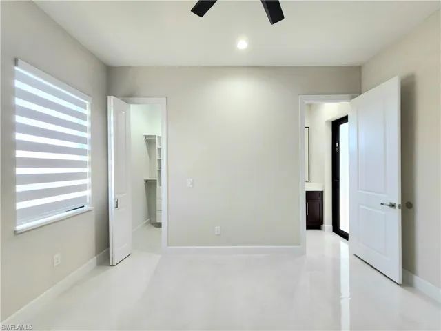 Unfurnished bedroom with a spacious closet, recessed lighting, light tile patterned floors, a ceiling fan, and connected bathroom