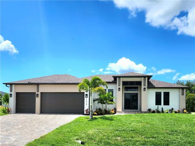 Prairie-style house featuring a front yard, stucco siding, an attached garage, decorative driveway, and roof with shingles