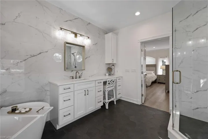 Ensuite bathroom featuring tile walls, a marble finish shower, vanity, a soaking tub, and recessed lighting