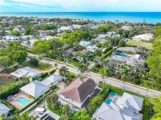 Aerial view of residential area featuring a nearby body of water and a pool