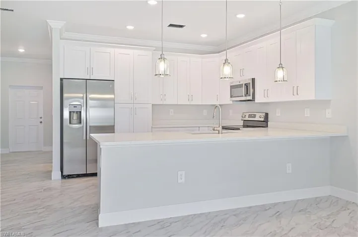 Kitchen featuring light tile floors, hanging light fixtures, sink, white cabinetry, and appliances with stainless steel finishes