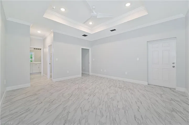 Tiled spare room featuring ornamental molding, ceiling fan, and a raised ceiling