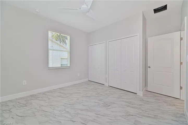 Unfurnished bedroom featuring multiple closets, ceiling fan, and light tile floors