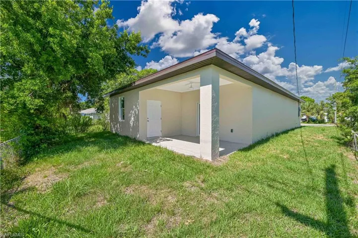 View of side of property with a patio area and a lawn