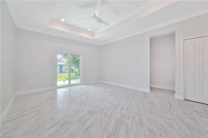 Tiled spare room with ceiling fan, a tray ceiling, and crown molding