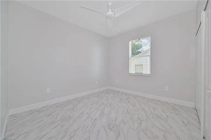 Empty room with ceiling fan and light tile floors