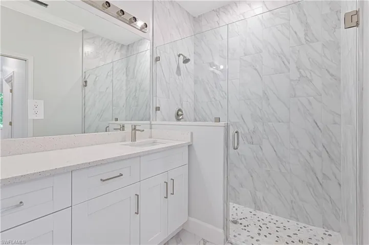 Bathroom with crown molding, a shower with shower door, tile floors, and vanity