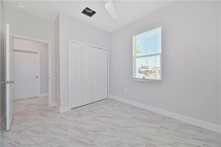 Unfurnished bedroom with ceiling fan, a closet, and light tile floors