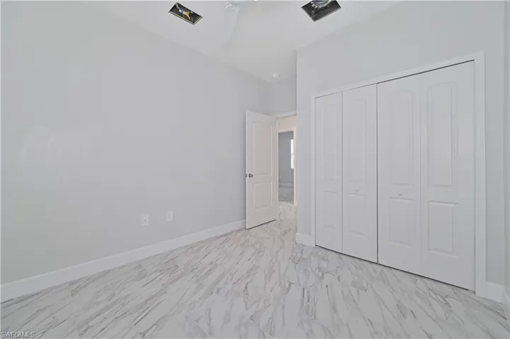 Unfurnished bedroom with a closet, ceiling fan, and light tile floors