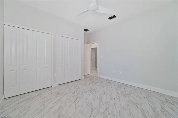 Unfurnished bedroom featuring multiple closets, ceiling fan, and light tile flooring