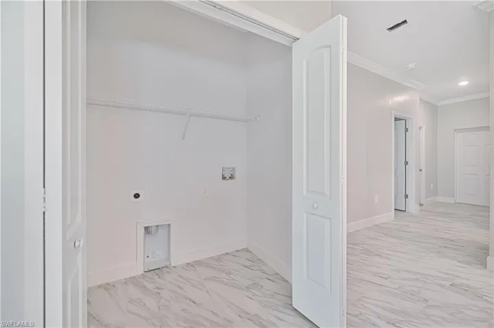 Washroom featuring electric dryer hookup, ornamental molding, light tile flooring, and hookup for a washing machine