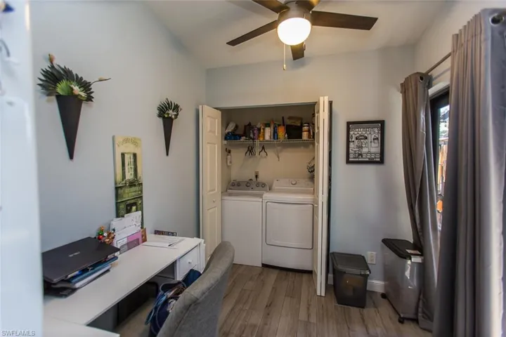 Laundry closet off kitchen tiled floors, a ceiling fan, washing machine and clothes dryer, and a desk