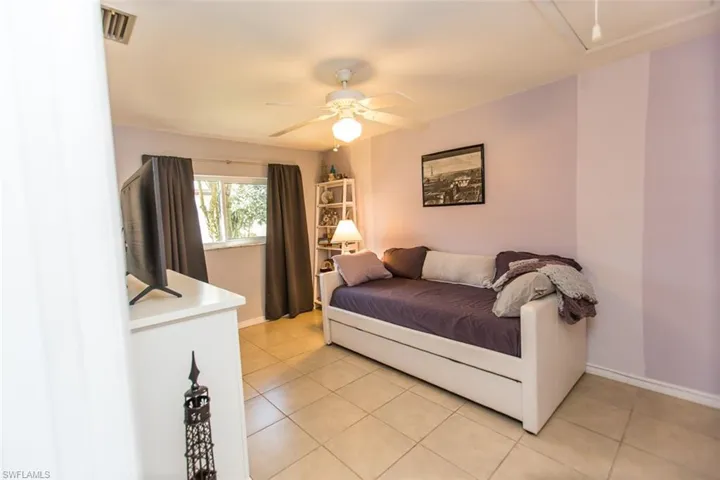 Guest Bedroom featuring attic access, light tile patterned floors, and ceiling fan