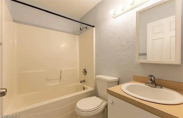 Full bath featuring a textured wall, vanity, and bathing tub / shower combination
