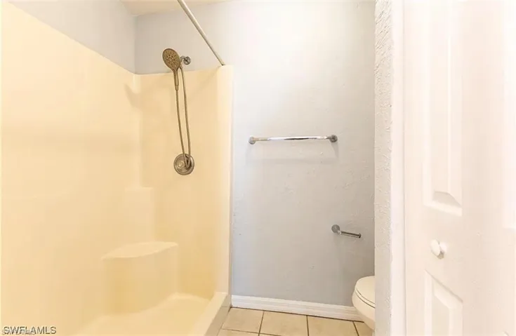 Full bath featuring a stall shower and light tile patterned floors