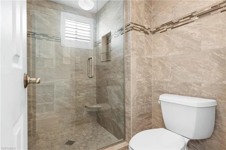Full bath with a shower stall and tile walls
