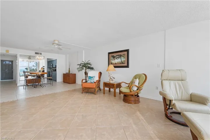 Living area featuring light tile patterned flooring, ceiling fan, and a textured ceiling