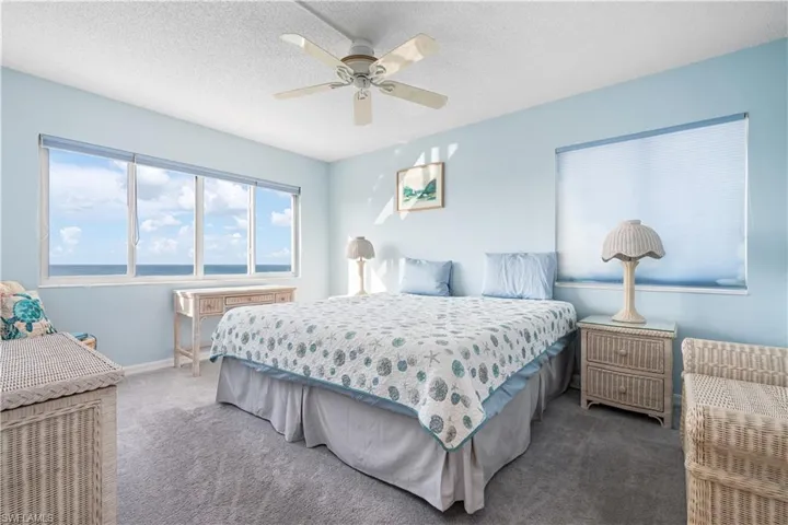 Carpeted bedroom with a textured ceiling, a ceiling fan, and a water view