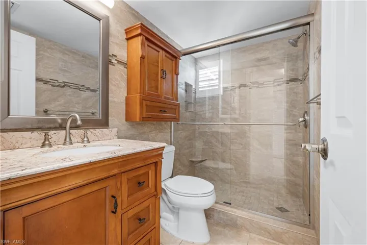 Bathroom featuring vanity, a stall shower, light tile patterned floors, and tile walls