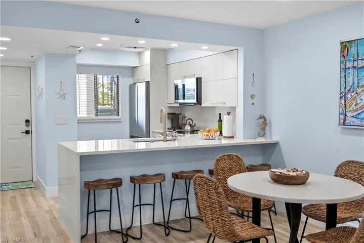 Kitchen featuring a kitchen breakfast bar, light countertops, white cabinets, appliances with stainless steel finishes, and a sink