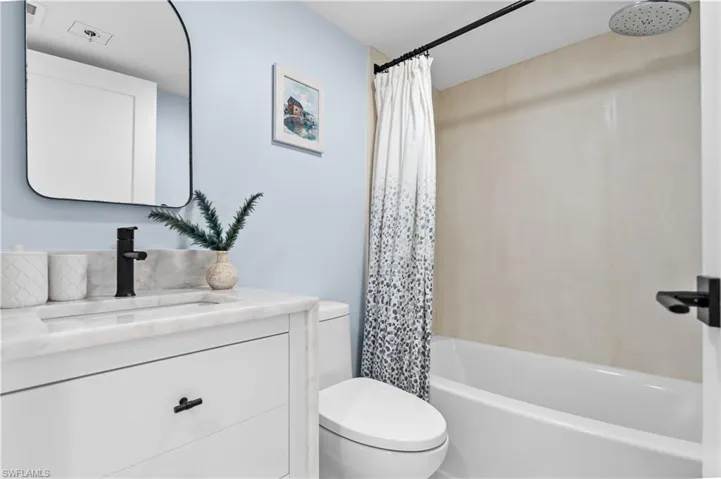 Bathroom featuring toilet, shower / bath combo with shower curtain, and vanity