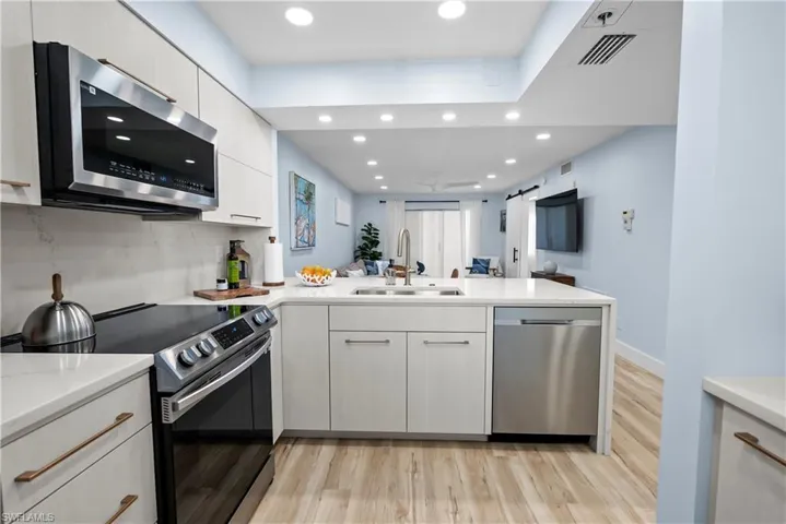 Kitchen featuring light wood-style floors, appliances with stainless steel finishes, a sink, and visible vents