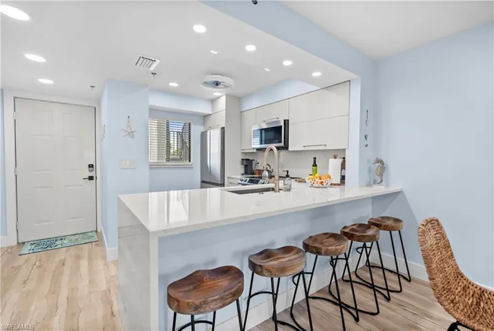 Kitchen with stainless steel appliances, a kitchen breakfast bar, and baseboards