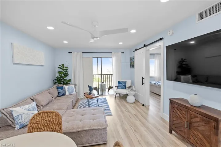 Living area featuring recessed lighting, a barn door, visible vents, and light wood finished floors