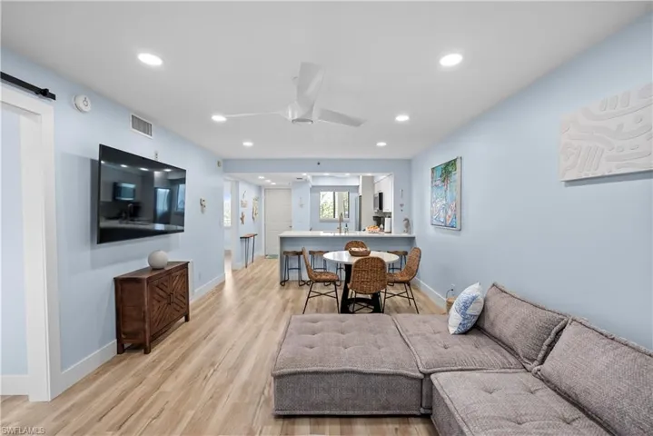 Living room with light wood-style flooring, visible vents, and recessed lighting
