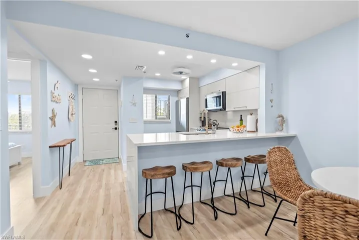 Kitchen featuring modern cabinets, a peninsula, white cabinetry, stainless steel appliances, and a breakfast bar area
