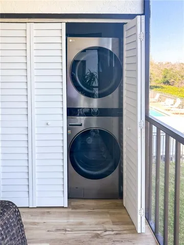 Laundry room featuring laundry area, wood finished floors, and stacked washer and clothes dryer