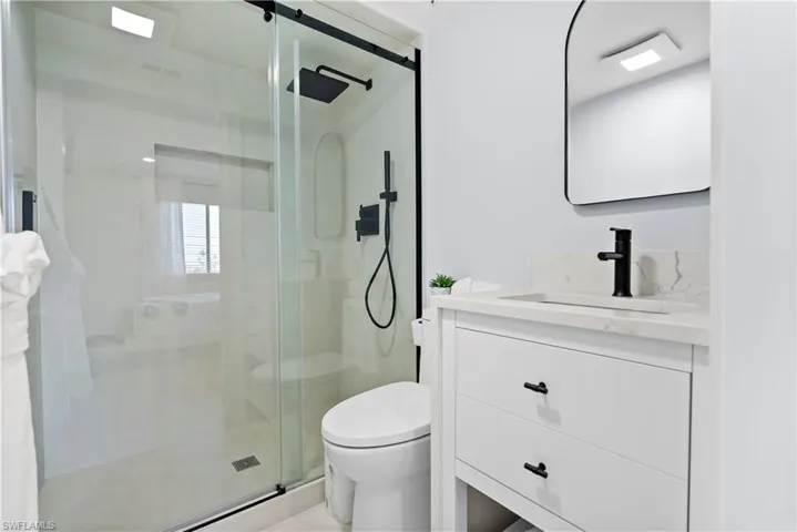 Full bath with toilet, a stall shower, and vanity